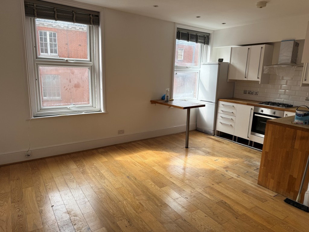 Lot: 196 - TWO-BEDROOM BALCONY FLAT IN CENTRAL LOCATION - Living room with two windows and kitchen area